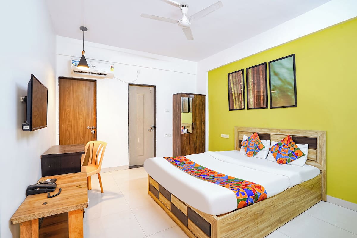 A bedroom with a bed, a desk, a chair, a wardrobe, and a ceiling fan.