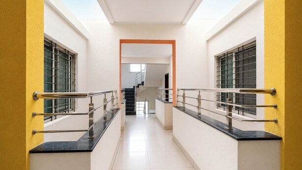Un corridoio con una scala, ringhiere metalliche e un lucernario.