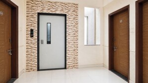 Un corridoio con una porta moderna che integra un display digitale, una parete strutturata e porte in legno su entrambi i lati.
