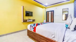 Una habitación de hotel con una cama, un televisor, una puerta y un espejo.