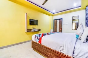 A hotel room with a bed, a TV, a door, and a mirror. - Fabhotel B Square (Visakhapatnam)
