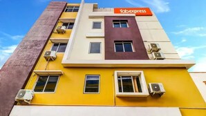 Un edificio de varios pisos con fachada amarilla, unidades de aire acondicionado y un letrero que dice 'fabexpress'.