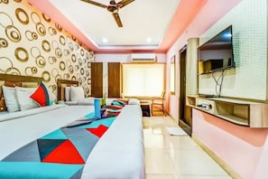 Une chambre d’hôtel équipée d’un lit, d’un bureau, d’une chaise, d’une télévision et d’un ventilateur de plafond.