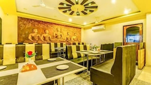 Un restaurante con cabinas, mesas y un mural de Buda.