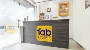 A reception desk with a 'fab hotels' sign, a clock, framed certificates, and a religious statue. - FabHotel Manjulam Regency (Indore)