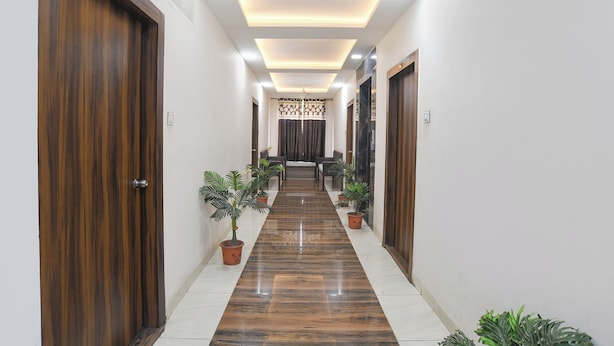 A hallway with wooden doors, potted plants, and a tiled floor. - FabHotel Manjulam Regency (Indore)