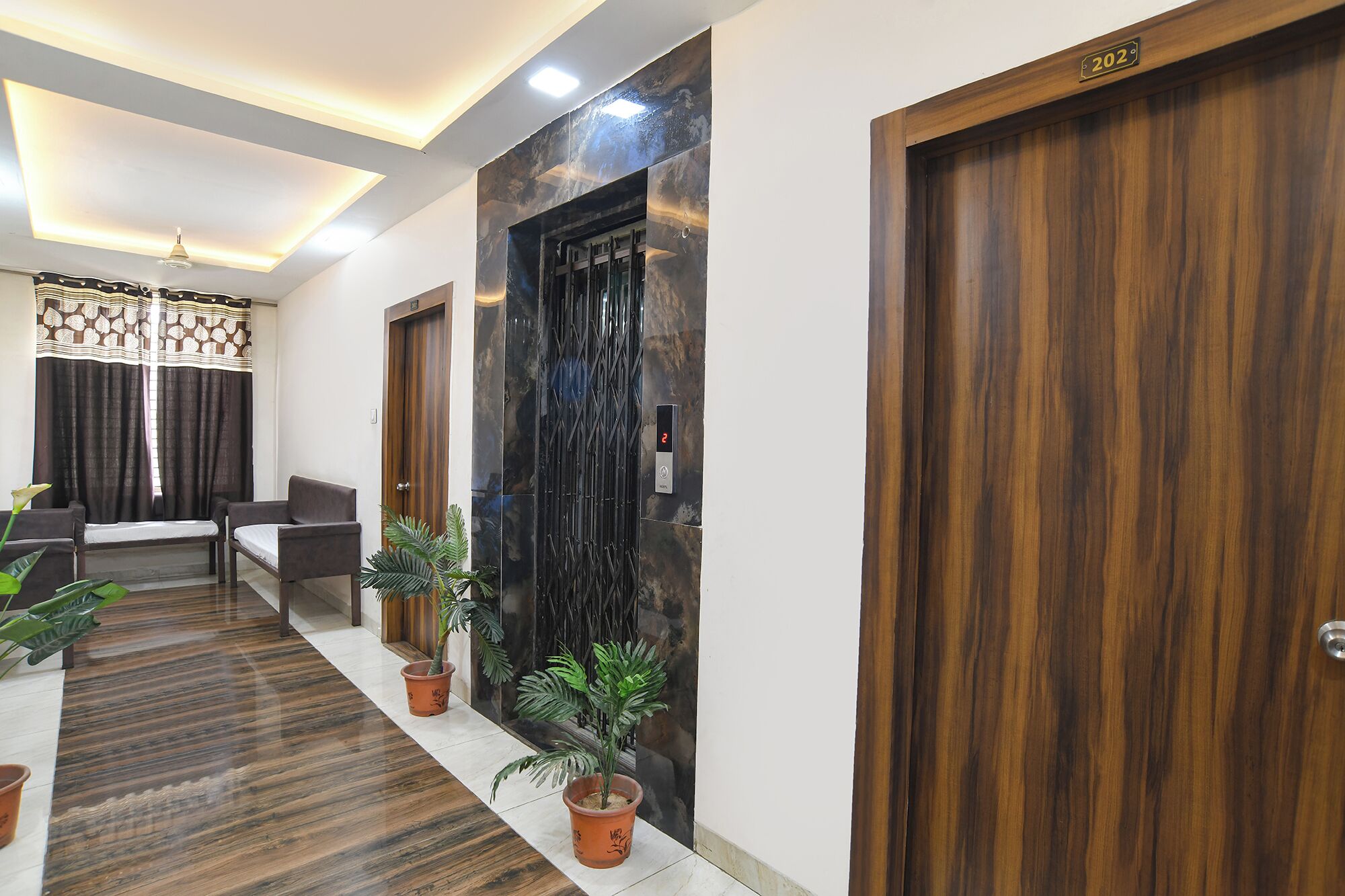 Un pasillo con puertas de madera, una mesa de recepción y plantas en macetas.