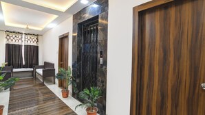 A hallway with wooden doors, a reception desk, and potted plants. - FabHotel Manjulam Regency (Indore)