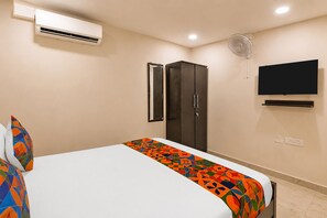 Un dormitorio con cama, aire acondicionado, armario, televisor y ventilador de pared.