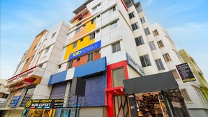 Et hotel med flere etager, hvor 'Fab Hotels' skiltet er tydeligt synligt, samt en reception og forskellige butikker i stueetagen.