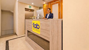 Et hotelreceptionsskrivebord med et 'fab hotels' skilt, en computer og et skilt på døren, der siger 'kontant betaling'.