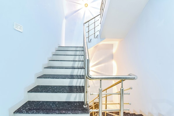 Una escalera con barandilla metálica y una silla al pie.