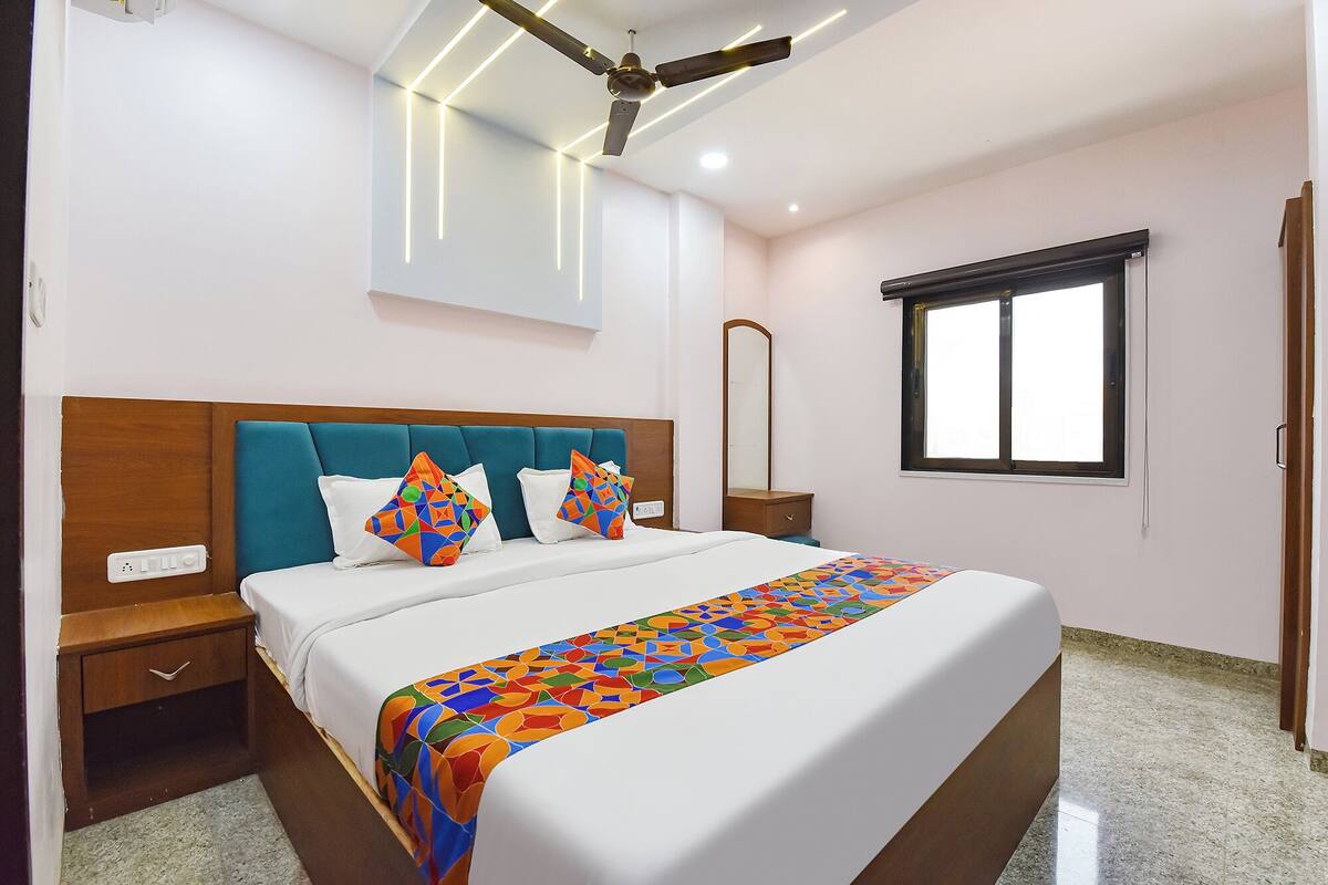 A hotel room with a bed, nightstands, a mirror, a window, and a ceiling fan.