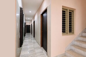 A hallway with a marble floor, a staircase, and doors leading to rooms. - Via D Stay Inn (Visakhapatnam)
