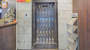 En elevator med et overvågningskamera, et overvågningsskilt og et skilt, der angiver elevatoren.
