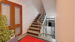 A staircase with a metal railing, a red carpet, and a wooden door with glass panels. - FabHotel Prestige Lake Ridge - Nr Durgam Cheruvu Lake Front Park (Hyderabad)