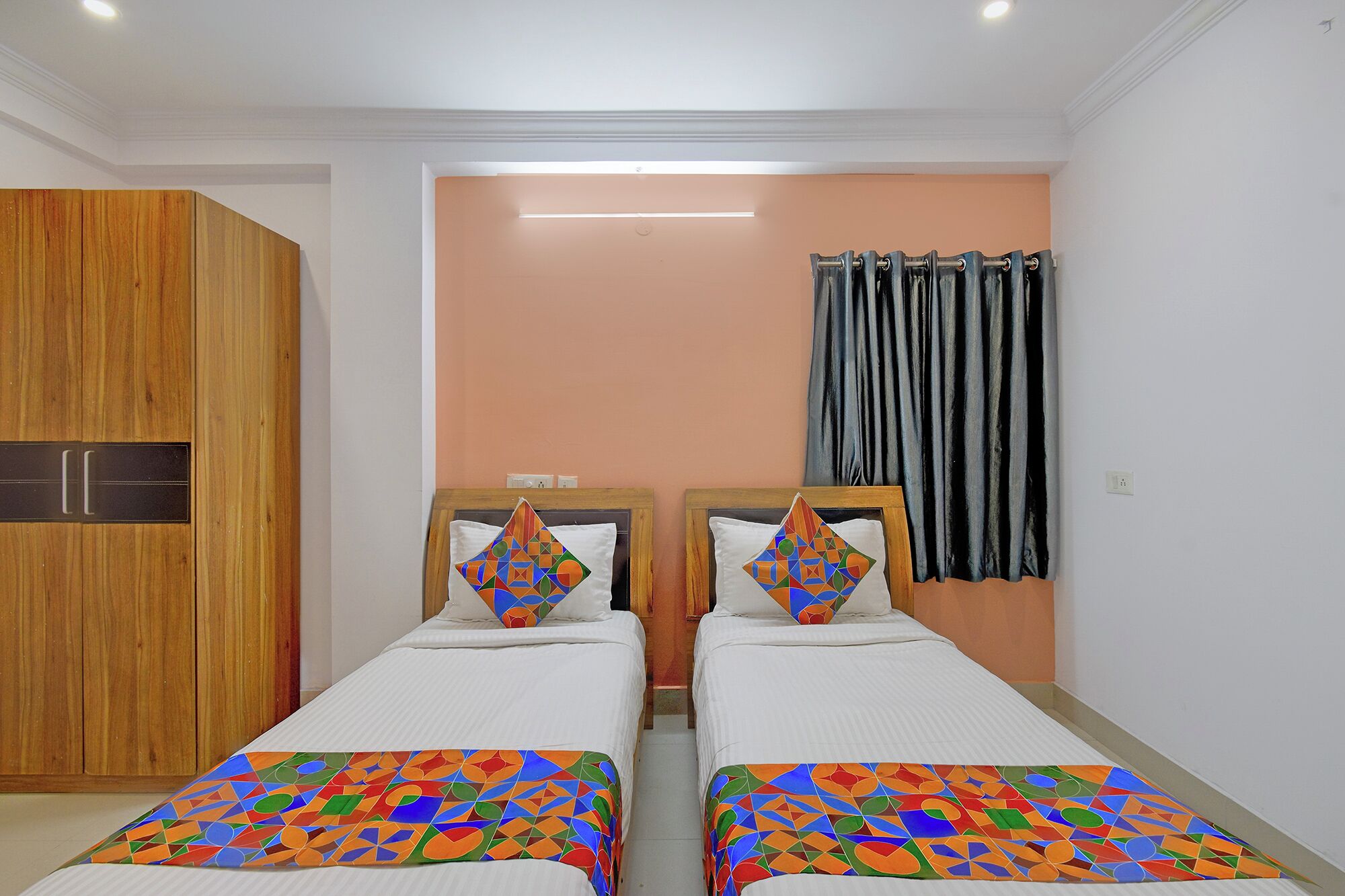 A bedroom with two beds, a wardrobe, and a curtain.