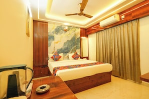 A hotel room with a bed, a ceiling fan, an air conditioning unit, a wooden desk, and a wall with a decorative map. - FabHotel Bash - Nagarbhavi (Bangalore)