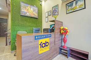 A reception desk with a 'Reception' sign, a computer, and a vase of flowers. - FabHotel Rudransh Residency - 1Km from Kashi Vishwanath Temple (Varanasi)