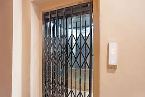 A door with a metal security gate and a digital lock. - FabHotel Rudransh Residency - 1Km from Kashi Vishwanath Temple (Varanasi)