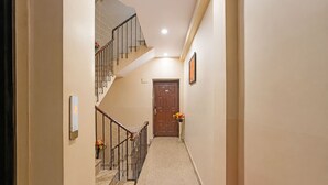 A hallway with a staircase, a door, and a framed picture on the wall. - Fahotel Rudransh Residency-1Km from Kashi Vishwanath Temple (Varanasi)