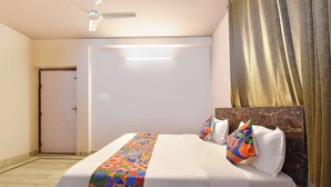 Een hotelkamer met een bed, een plafondventilator, een deur en een gordijn.