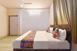 Quarto de hotel com cama, ventilador de teto, porta e cortina.
