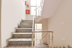 Eine Treppe mit Granitstufen und Metallgeländern, die zu einer Zwischenebene mit einem Fenster führt.