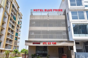 Um edifício com várias andares, varandas e uma placa com a inscrição 'HOTEL BLUE PRIME'.