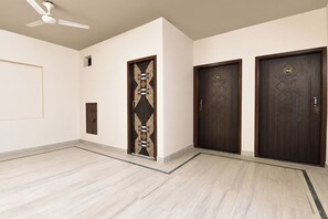 A hotel room with a ceiling fan, a door with a number plate, and a tiled floor. - FabHotel Blue Prime - Nr Suvira Hospital (Jaipur)