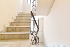 Escadaria com degraus de mármore e corrimão de ferro forjado.