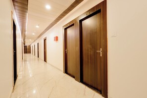 Un pasillo de hotel con puertas de madera, numeradas 101 y 102, y un detector de incendios en la pared.