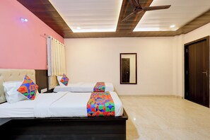 Habitación de hotel con dos camas, ventilador de techo, espejo y puerta.
