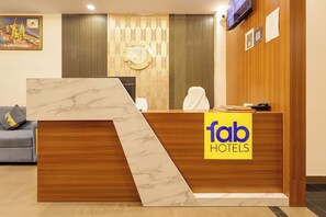 Un mostrador de recepción de hotel con encimera de mármol, un panel de madera a la derecha y el logotipo de 'fab hotels'.