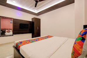 Un dormitorio con cama, armario, televisor y lámpara en el techo.