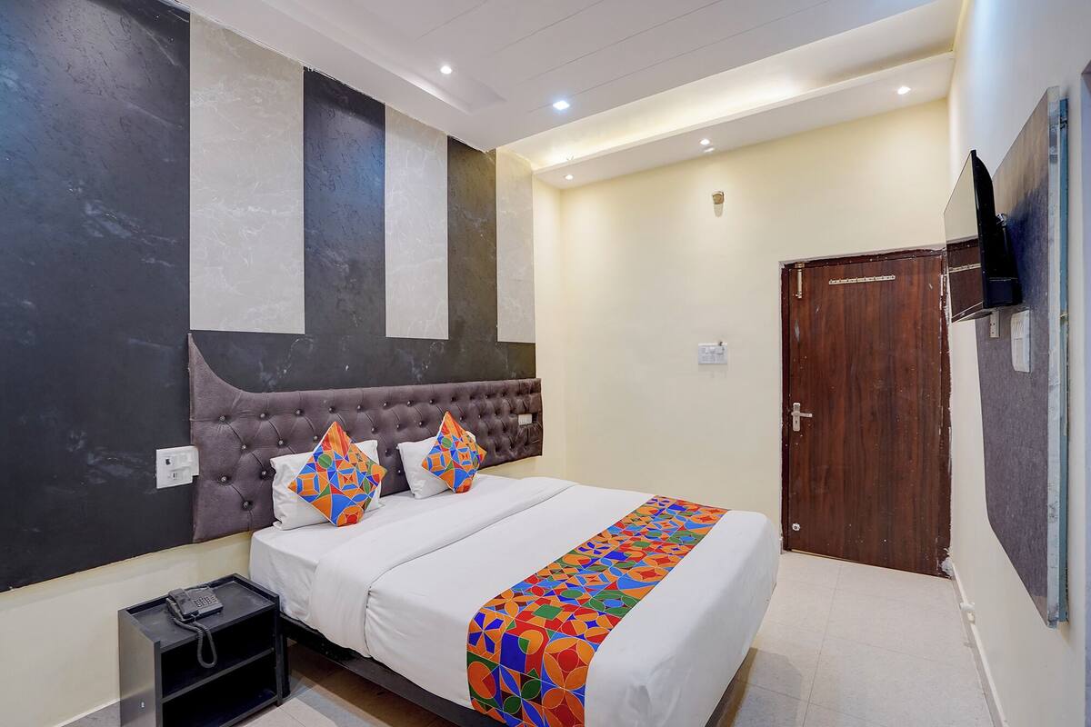 Un dormitorio con una cama grande, un teléfono en la mesita de noche y una puerta de madera.