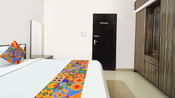Habitación de hotel con cama, armario, puerta y toma de corriente.