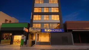 Um hotel de vários andares com uma placa de destaque para 'fab hotels' e uma placa para 'Hotel Utsav Palace'.