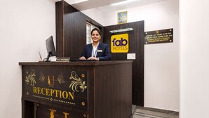 Uma receção com uma placa a indicar 'fab hotels' e um aviso acima com os horários de entrada.