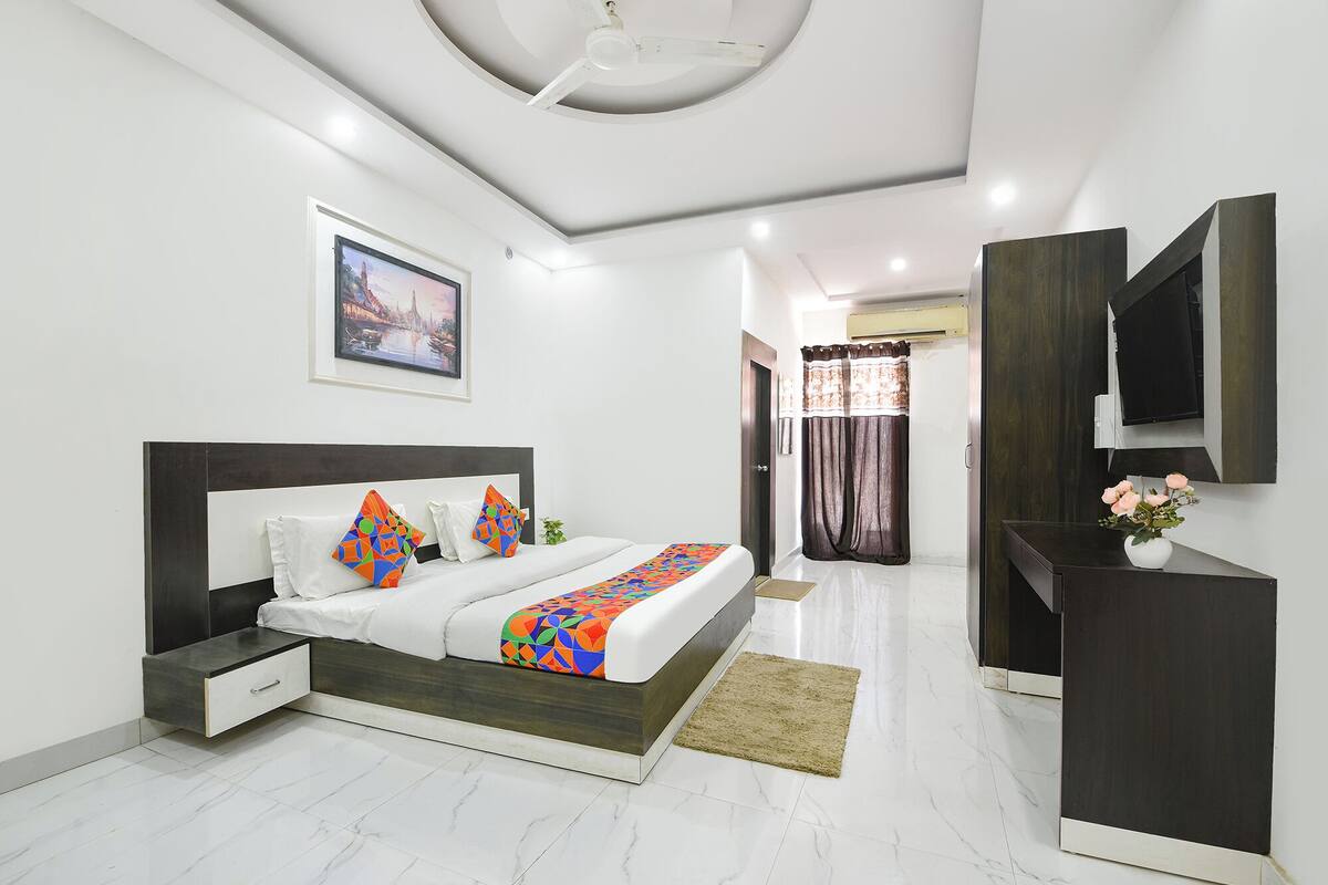 A modern bedroom with a bed, bedside tables, a TV, and a painting on the wall.