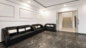 A modern waiting area with black leather sofas and a marble floor. - Fabhotel Rajvanshi Palace (Gurugram)