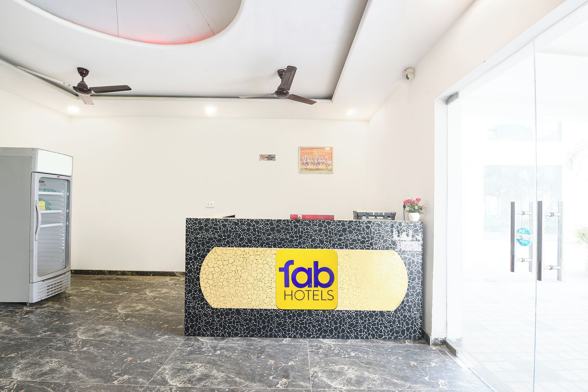 Een receptiebalie met een 'fab hotels' bord, een beveiligingscamera en een betegelde vloer.