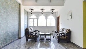 Una habitación con piso de mármol, dos sofás, una mesa y un ventanal con vidrios decorativos.