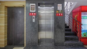 An elevator with a digital display, a notice sign, and a red safety sign. - Fabhotel Alfaa Inn (Bangalore)