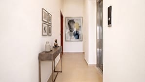 A hallway with a wooden console table, framed artwork, and a door with a digital lock.