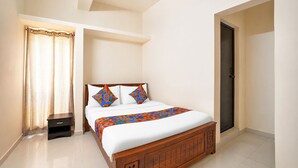 A bedroom with a bed, a nightstand, a door, and a window with curtains.