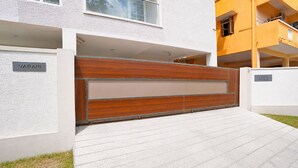 A modern building with a wooden gate, a nameplate reading 'VARAHI,' and a sign indicating 'S Chira Plot No. 65.'