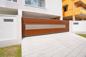 A modern building with a wooden gate, a nameplate reading 'VARAHI,' and a sign indicating 'S Chira Plot No. 65.'