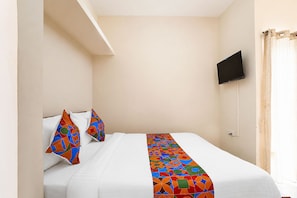 A hotel room with a bed, a TV mounted on the wall, and a curtain. - Fabhotel Nimalan Residency (Chennai)
