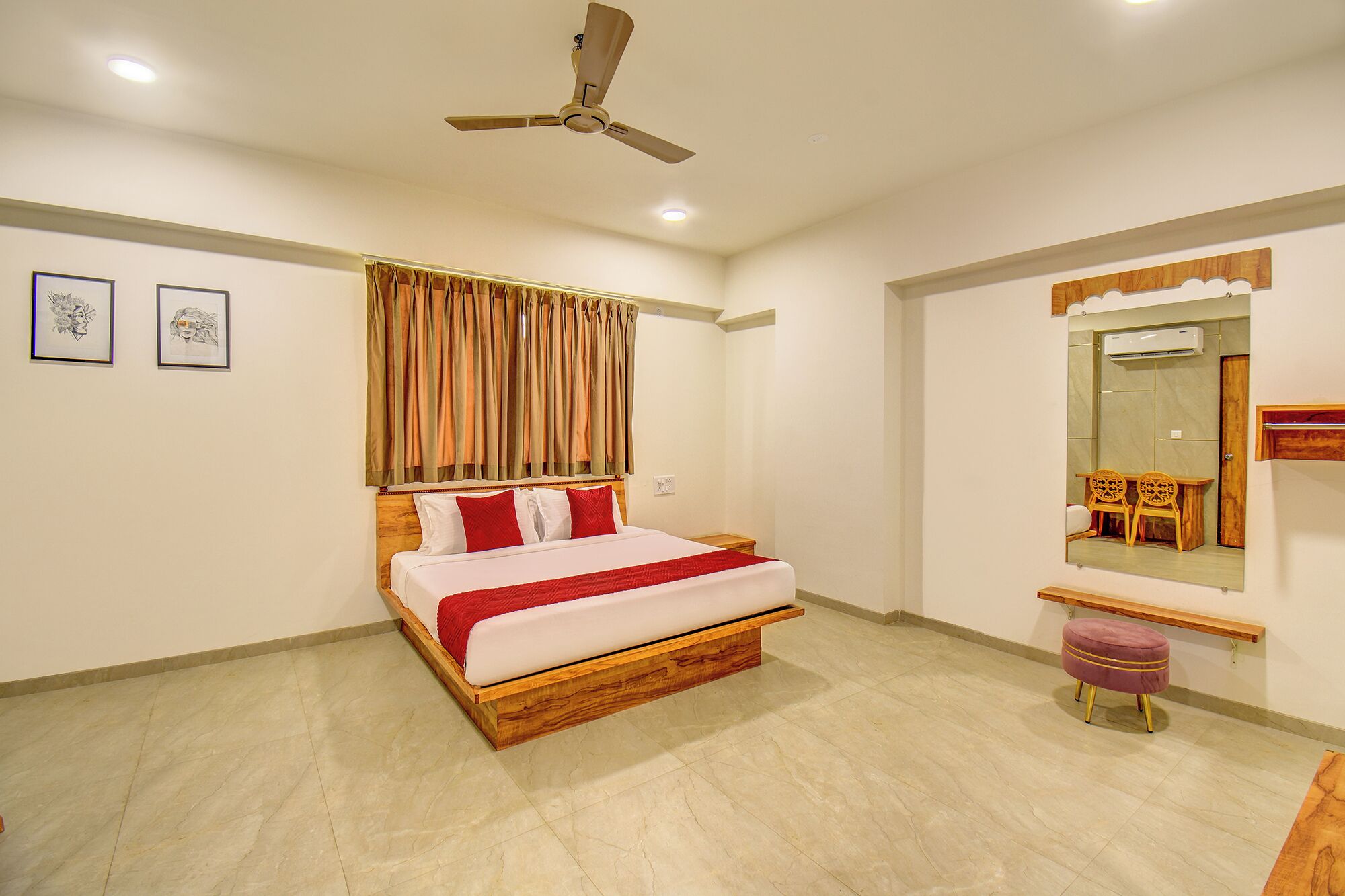 A hotel room with a bed, a ceiling fan, a mirror, and a small table.